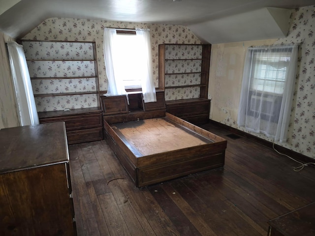 unfurnished bedroom featuring lofted ceiling, visible vents, dark wood finished floors, and wallpapered walls