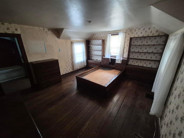 unfurnished bedroom featuring vaulted ceiling, wainscoting, dark wood-style floors, and wallpapered walls