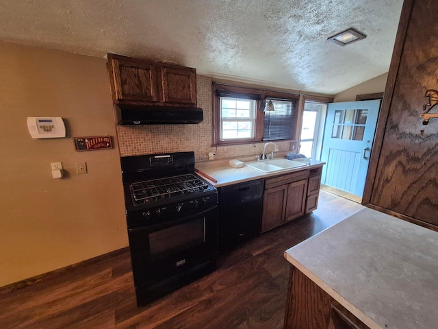 kitchen featuring dark wood-type flooring, extractor fan, a textured ceiling, black appliances, and a sink