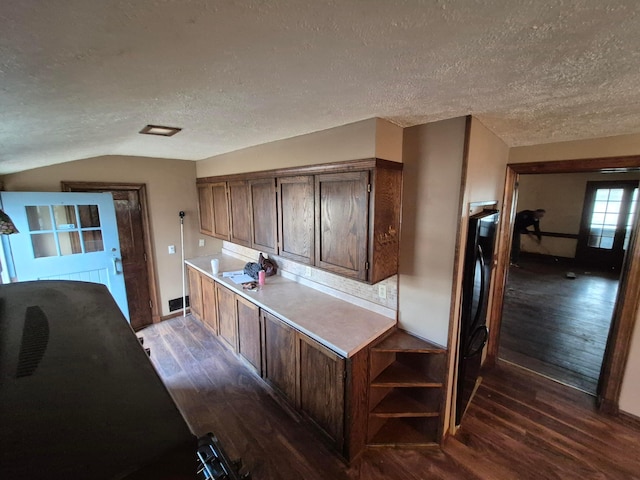 kitchen featuring lofted ceiling, dark wood-style flooring, light countertops, and dark brown cabinetry