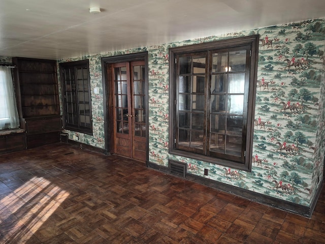 empty room with baseboards, visible vents, and wallpapered walls