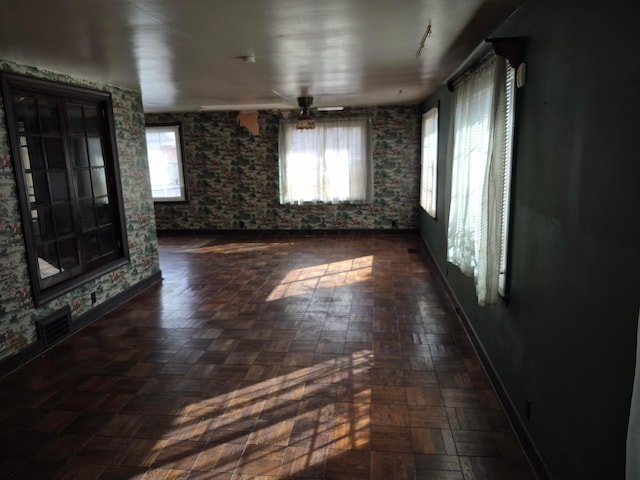 empty room with plenty of natural light, visible vents, ceiling fan, and baseboards