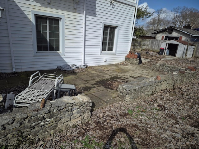 view of patio featuring fence, an outdoor structure, and a storage unit