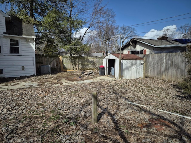 view of yard featuring a fenced backyard, an outdoor structure, a storage shed, and central air condition unit