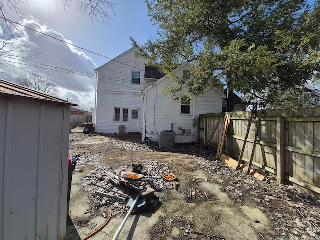 rear view of house featuring central AC and fence