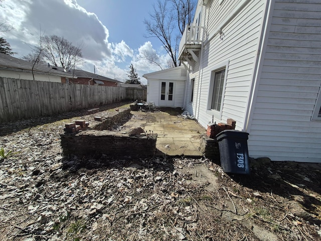 view of yard with a balcony, a patio area, a fenced backyard, and french doors