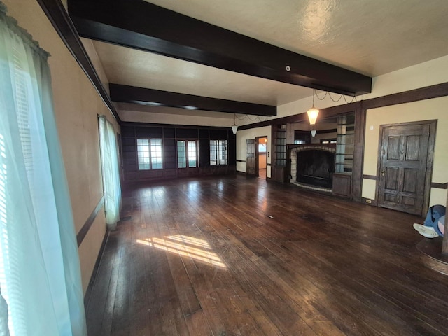 unfurnished living room with a fireplace, beamed ceiling, and hardwood / wood-style flooring