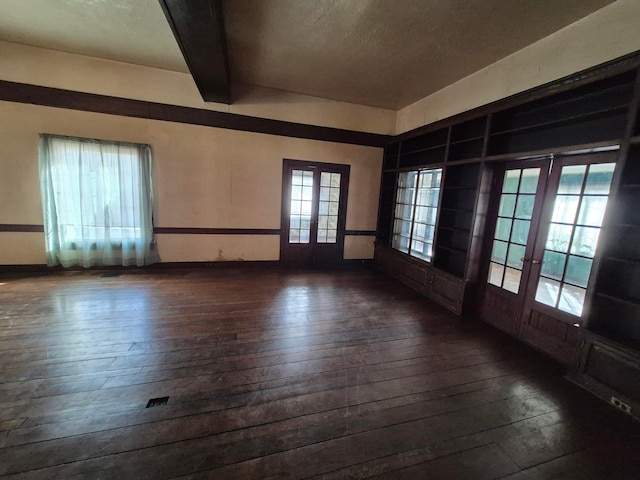 empty room featuring french doors, dark wood finished floors, and beam ceiling