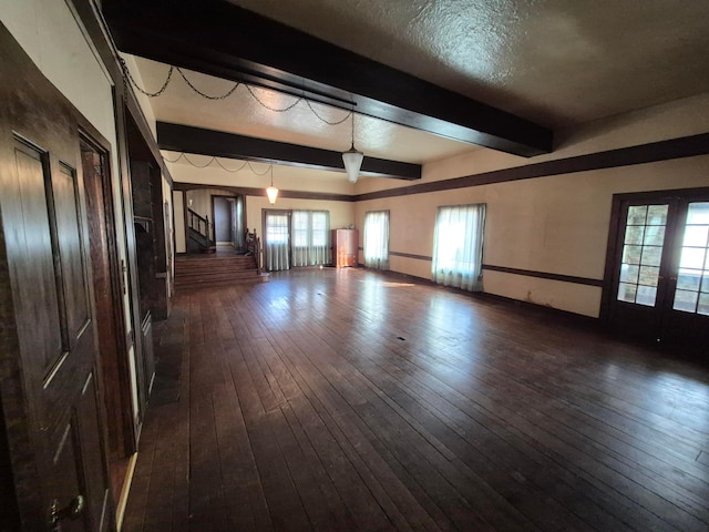 empty room featuring a textured ceiling, dark wood-type flooring, stairs, french doors, and beam ceiling