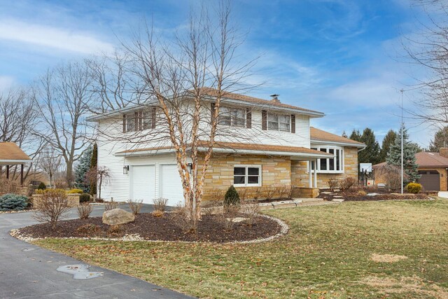 split level home featuring driveway, stone siding, a garage, and a front lawn