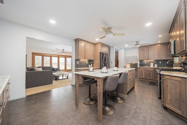 kitchen featuring recessed lighting, stainless steel appliances, a kitchen island, open floor plan, and backsplash