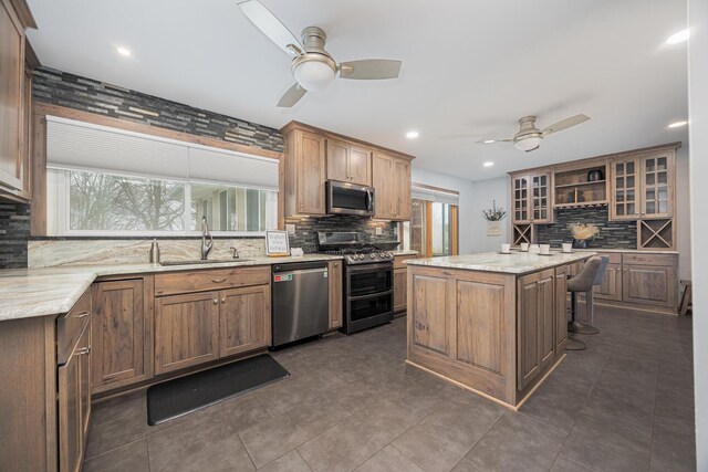 kitchen with stainless steel appliances, backsplash, glass insert cabinets, a sink, and a kitchen island