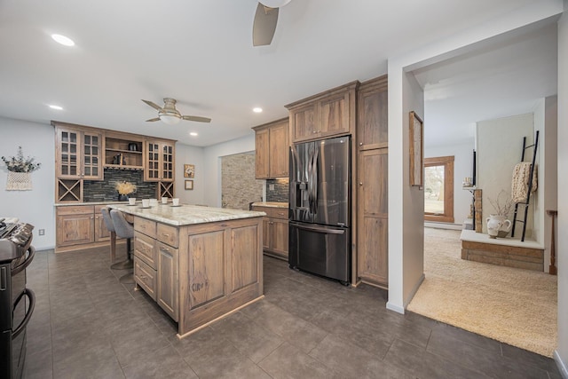 kitchen with a ceiling fan, a center island, glass insert cabinets, and stainless steel fridge with ice dispenser