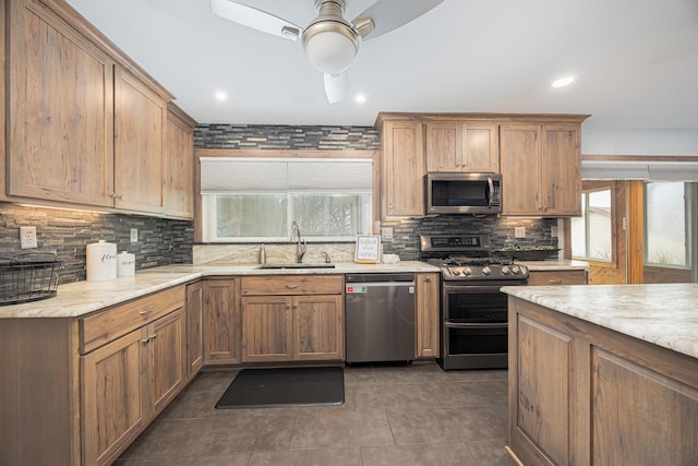 kitchen with decorative backsplash, a ceiling fan, stainless steel appliances, dark tile patterned floors, and a sink