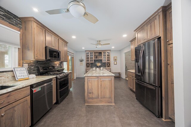 kitchen featuring appliances with stainless steel finishes, backsplash, a kitchen island, and a ceiling fan