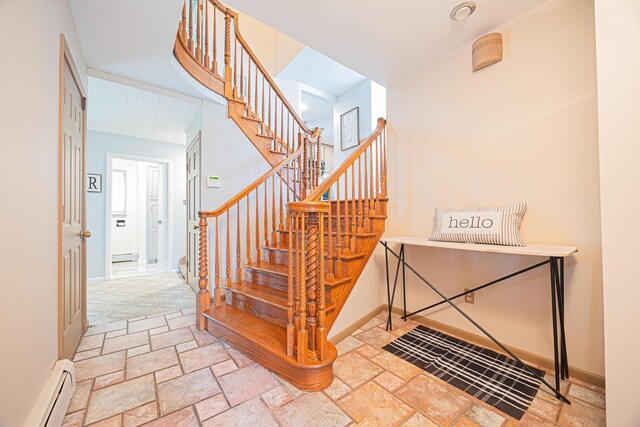 stairway featuring a baseboard radiator, baseboards, and stone tile floors