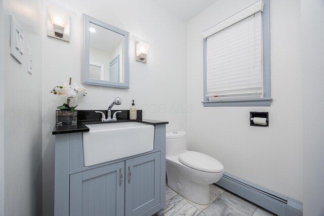 half bath with toilet, marble finish floor, baseboard heating, and vanity