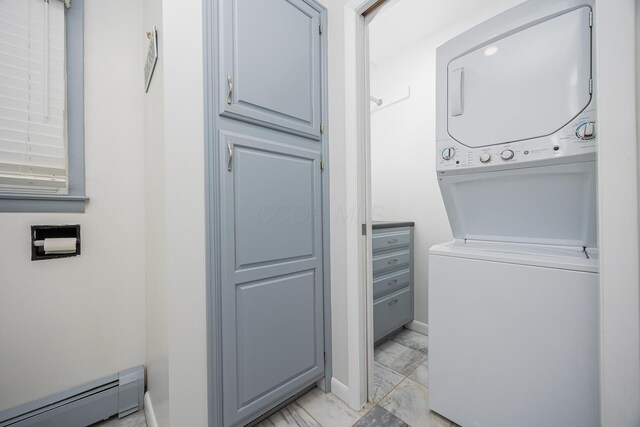 clothes washing area featuring laundry area, baseboards, marble finish floor, stacked washing maching and dryer, and a baseboard heating unit