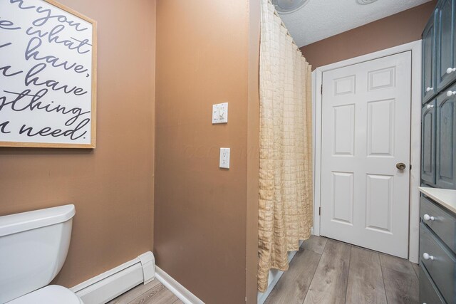 bathroom featuring a baseboard radiator, a textured ceiling, toilet, and wood finished floors