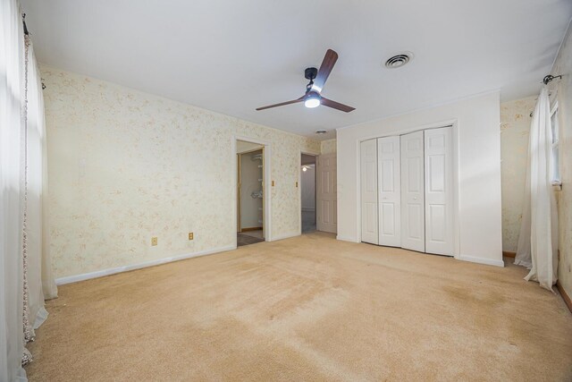 unfurnished bedroom with wallpapered walls, baseboards, visible vents, carpet flooring, and a closet