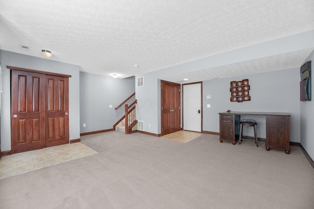foyer entrance with stairs, a textured ceiling, carpet, and baseboards