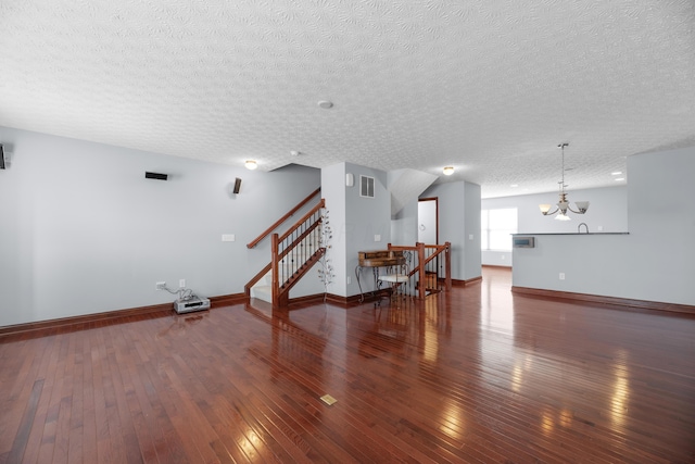 living room featuring visible vents, hardwood / wood-style floors, a chandelier, baseboards, and stairs