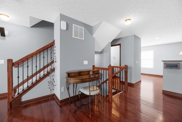 dining space with wood-type flooring, a textured ceiling, visible vents, and baseboards