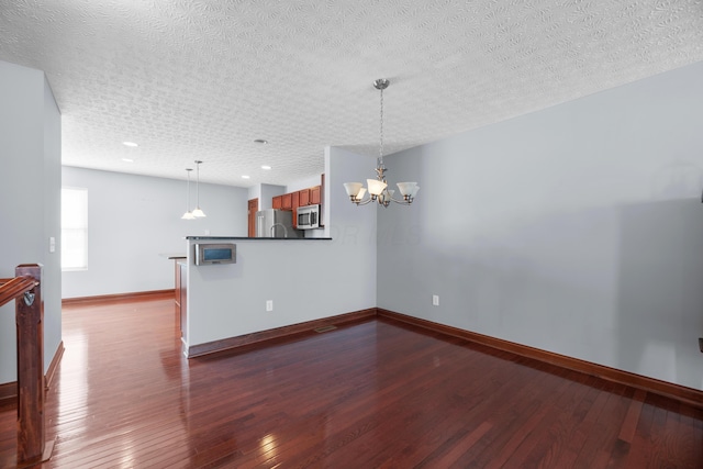 interior space with an inviting chandelier, a textured ceiling, baseboards, and dark wood-type flooring