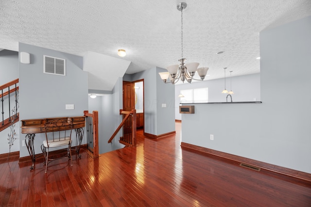 dining space featuring baseboards, hardwood / wood-style floors, visible vents, and a notable chandelier