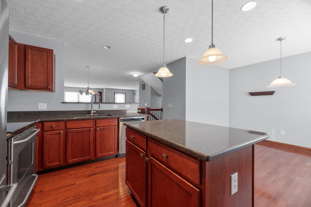 kitchen featuring dark wood-style floors, a textured ceiling, appliances with stainless steel finishes, and a sink