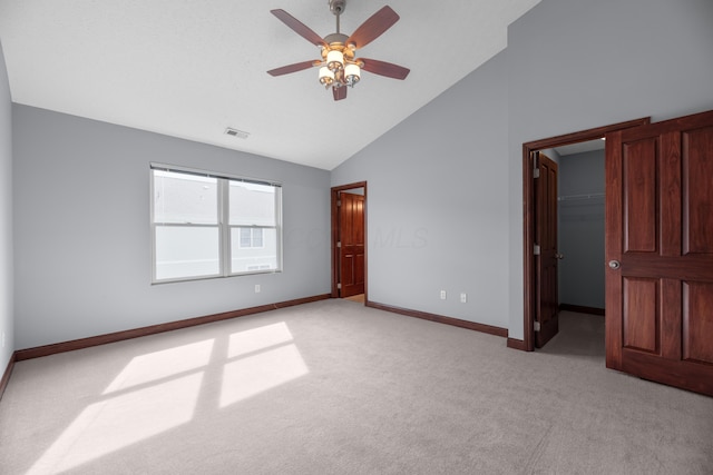 unfurnished bedroom with high vaulted ceiling, light colored carpet, visible vents, baseboards, and a walk in closet
