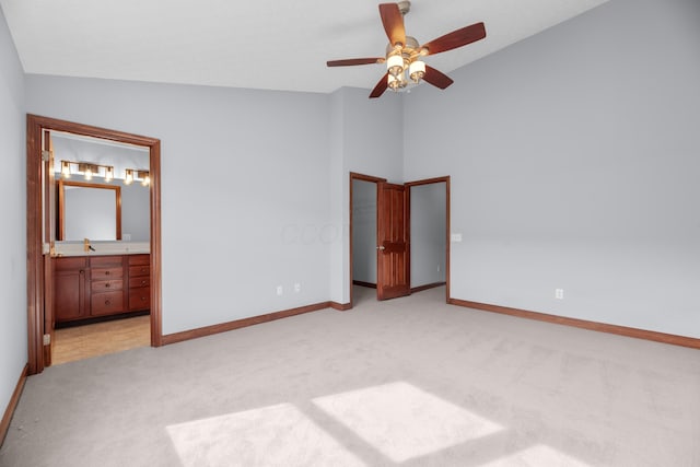 unfurnished bedroom featuring a walk in closet, lofted ceiling, light colored carpet, connected bathroom, and baseboards