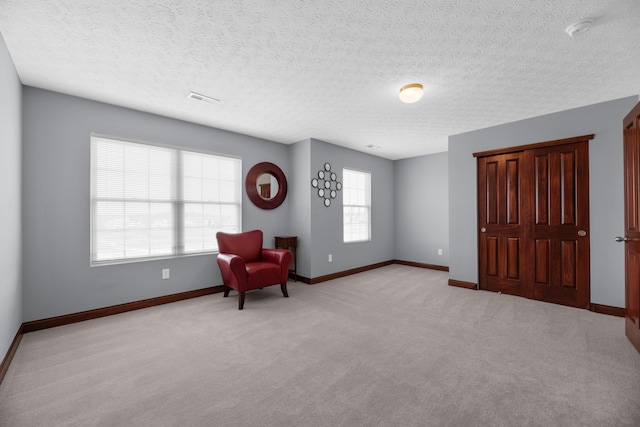 unfurnished room featuring light carpet, a textured ceiling, visible vents, and baseboards