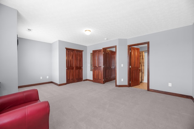 unfurnished room with visible vents, baseboards, a textured ceiling, and light colored carpet