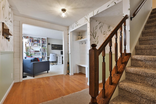 interior space featuring a textured ceiling, wood finished floors, and baseboards