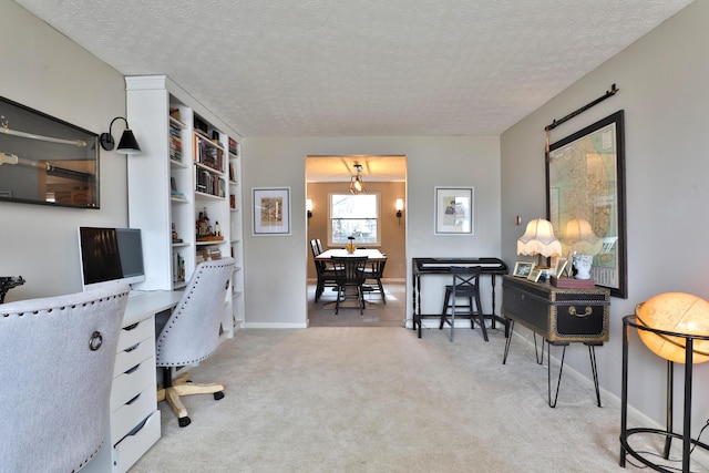 carpeted office featuring built in desk, baseboards, and a textured ceiling