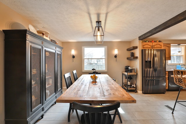 dining area featuring light tile patterned floors and a textured ceiling