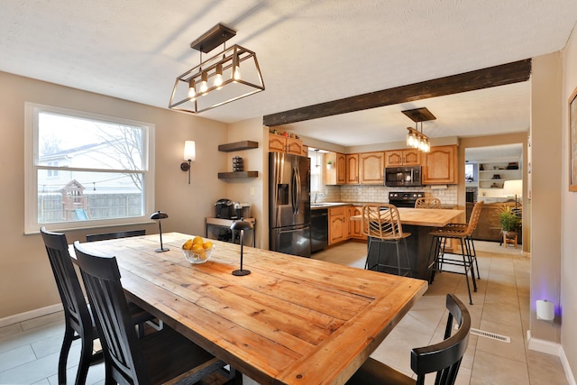 dining area with light tile patterned floors, a textured ceiling, beam ceiling, and baseboards