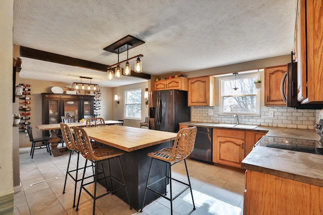 kitchen featuring a breakfast bar, tasteful backsplash, appliances with stainless steel finishes, a sink, and butcher block countertops