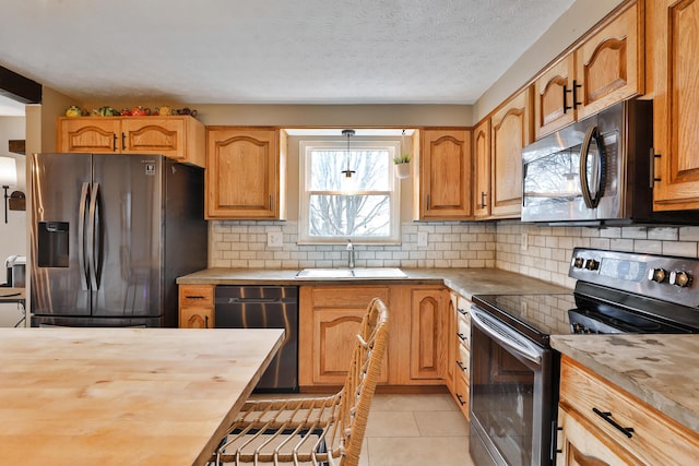 kitchen with light tile patterned floors, appliances with stainless steel finishes, wooden counters, and a sink