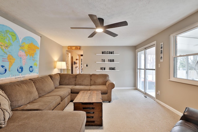 living room featuring ceiling fan, a textured ceiling, baseboards, and carpet flooring