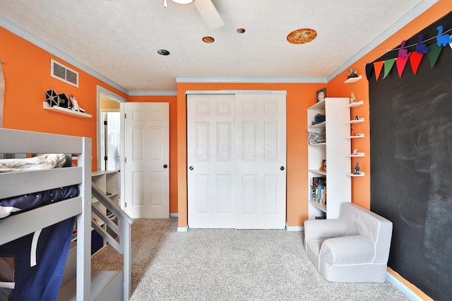 bedroom with carpet floors, crown molding, a closet, visible vents, and a textured ceiling