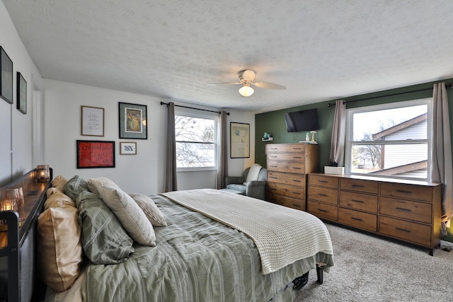 bedroom featuring light carpet, ceiling fan, and a textured ceiling