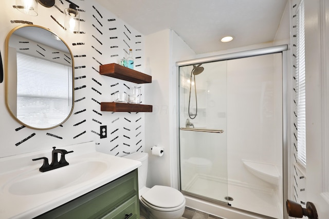 bathroom featuring vanity, a shower stall, and toilet