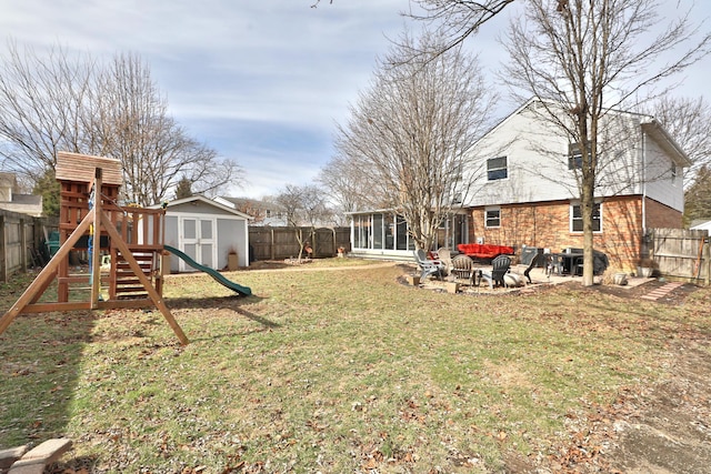 view of yard featuring a playground, a sunroom, a shed, a fenced backyard, and an outdoor structure