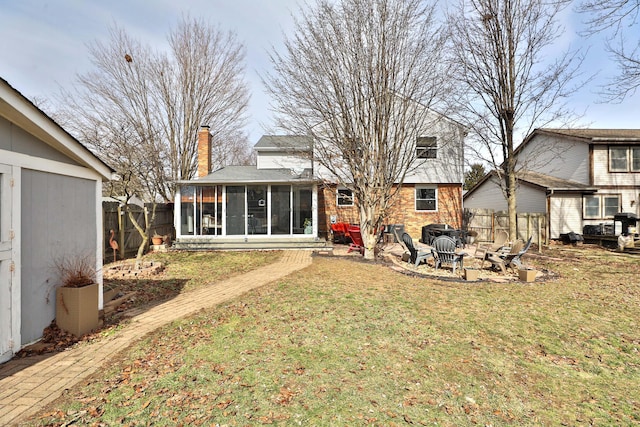 back of property with a fire pit, fence, a sunroom, a lawn, and a chimney