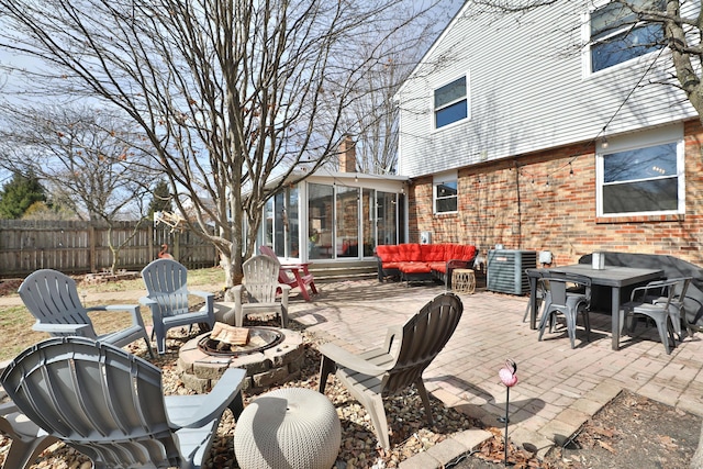 view of patio featuring central AC, an outdoor living space with a fire pit, fence, and a sunroom