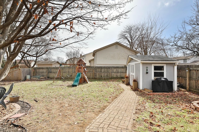 view of yard with a fenced backyard, an outdoor structure, and a playground