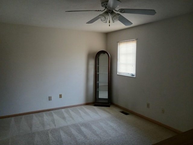 unfurnished room with baseboards, ceiling fan, visible vents, and light colored carpet