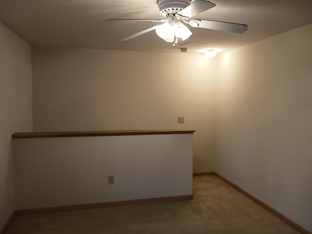 spare room with baseboards, a ceiling fan, and light colored carpet